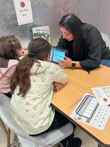 College student working with two elementary school students using an iPad